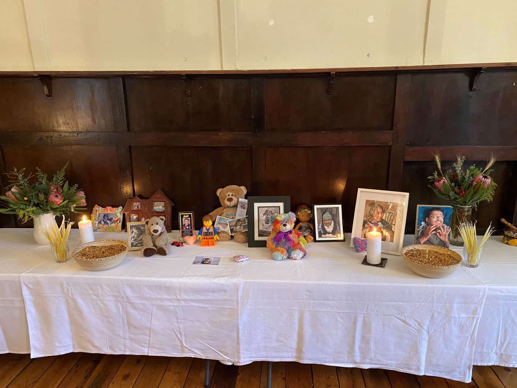 A long table is set with photos and mementos of children. There are candles lit in their memory.