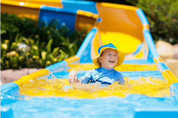 Image of a child going down a water slide, he is smiling and laughing.