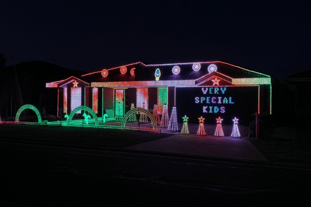 Image of a house lit up with Christmas lights. The words Very Special Kids are spelled out in lights.