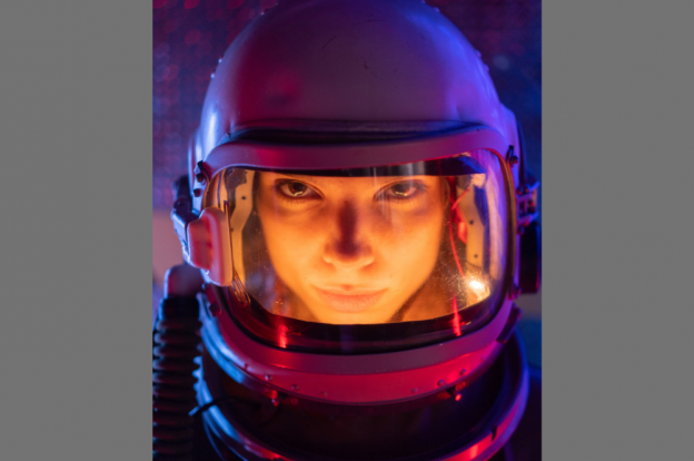 Close up image of a person's face, wearing an astronaut helmet.