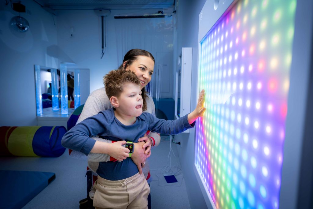 A young boy and his mum enjoy the light display in the multi-sensory room