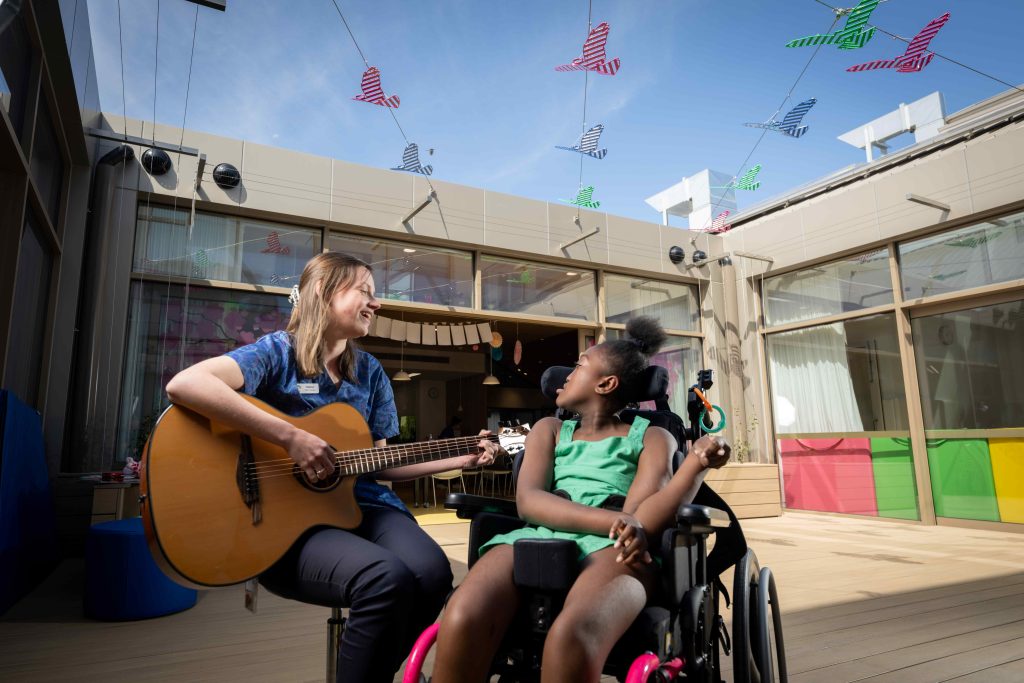 Very special child Mia and music therapist Helena enjoy time in the central courtyard.